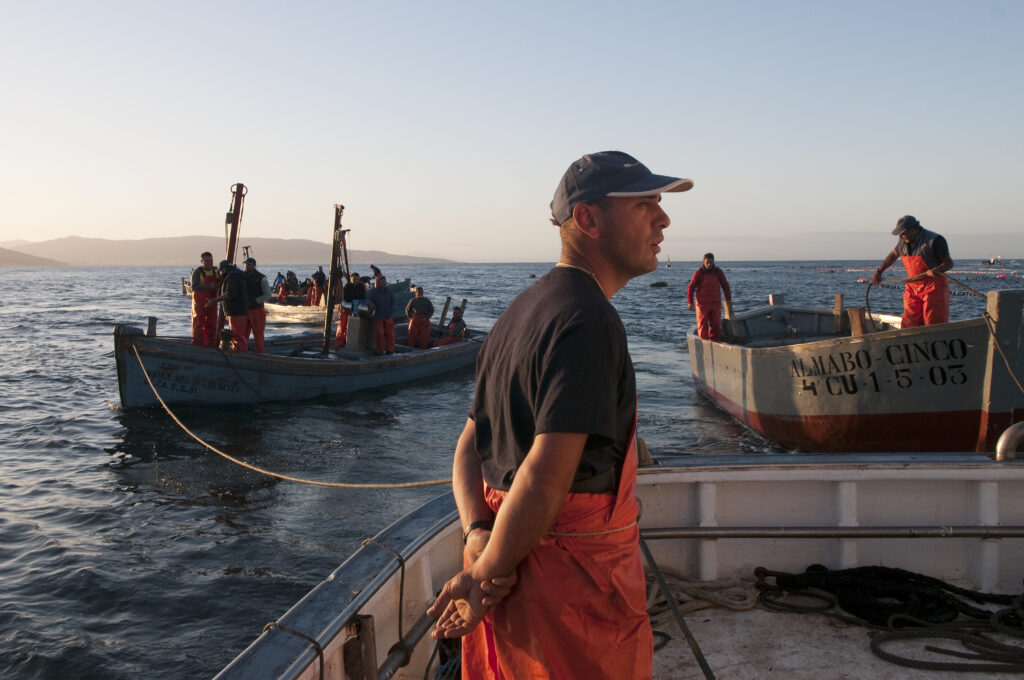 Uno de los pescadores en el barco con el amanecer de fondo